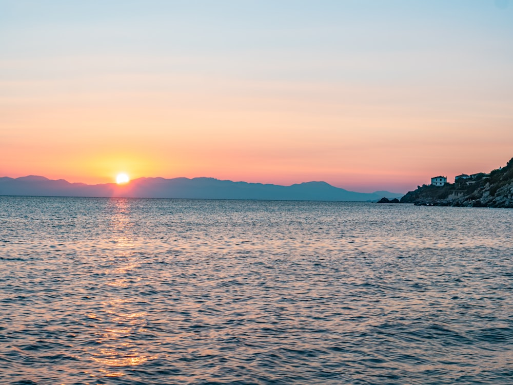 a large body of water with a sunset in the background