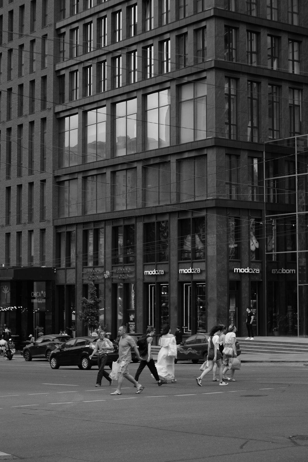 a group of people crossing a street in front of a tall building