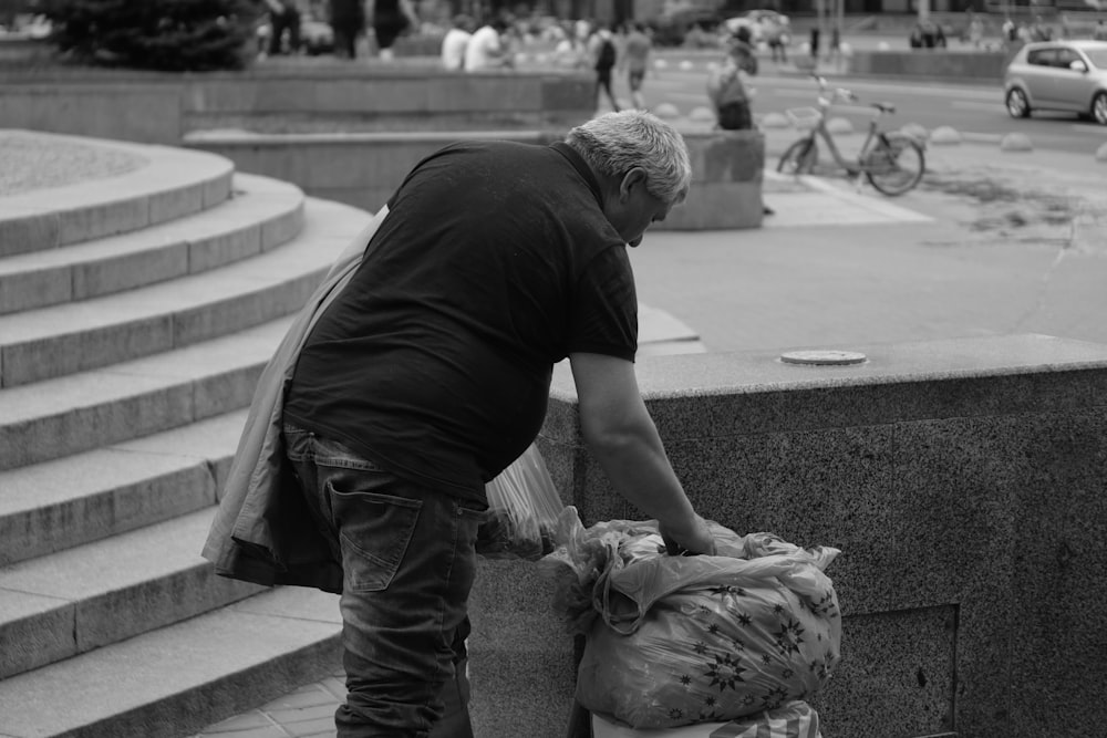 a man is picking up trash on the side of the street