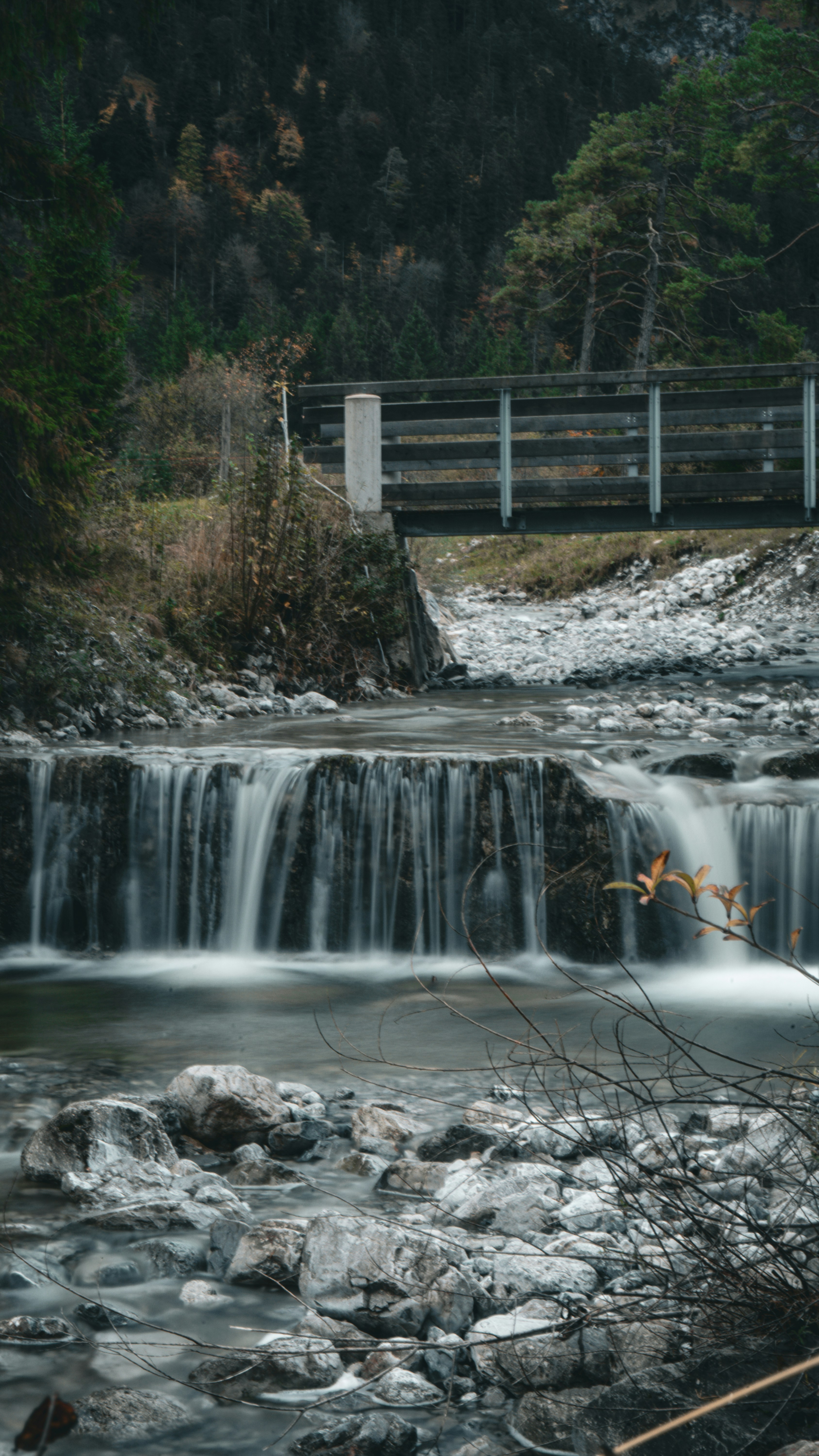 a small waterfall with a bridge in the background