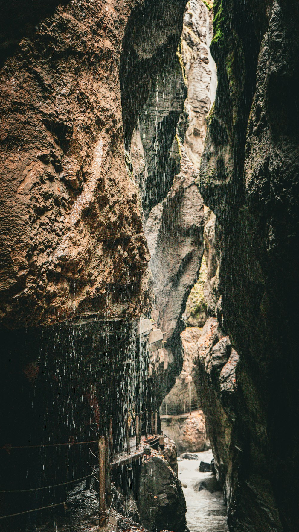 a man standing in a cave next to a stream of water