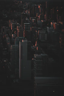 Wide cinematic frame of a shadowy cityscape at night, bathed in deep black and gold hues, evoking an atmosphere of secretive encounters.