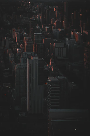 Wide cinematic frame of a shadowy cityscape at night, bathed in deep black and gold hues, evoking an atmosphere of secretive encounters.