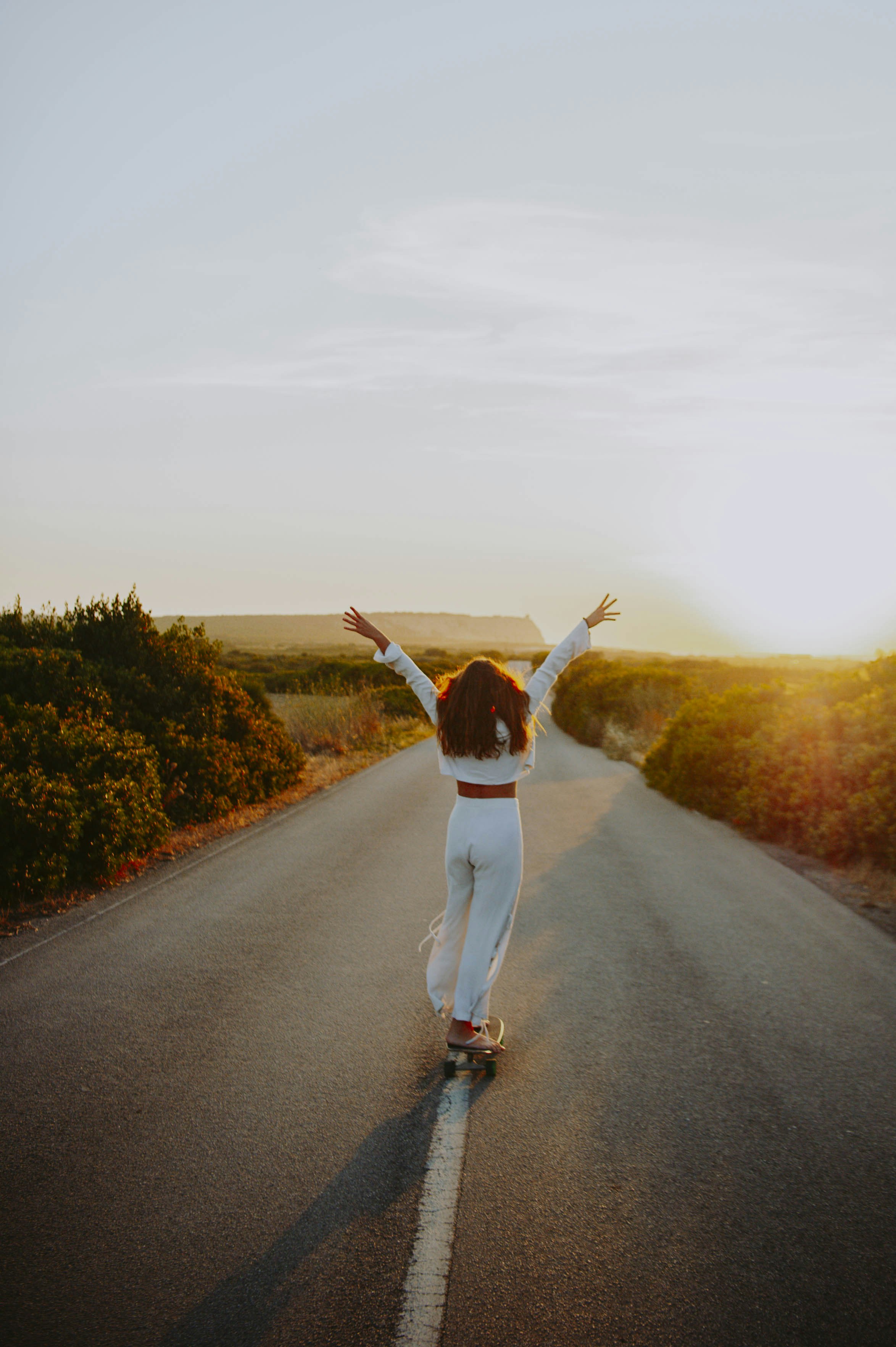 a woman riding a skateboard down a road