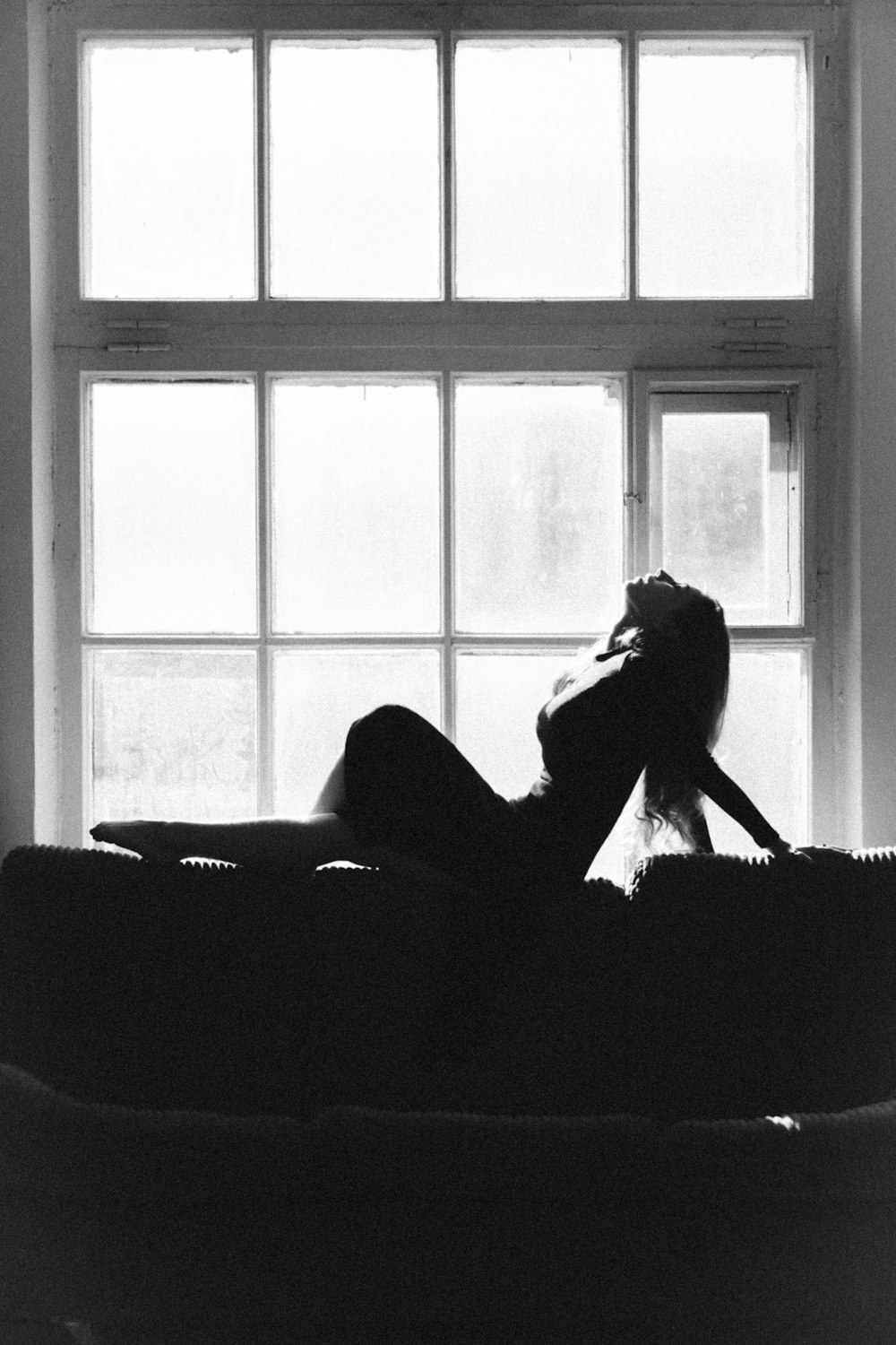 a woman laying on a couch in front of a window