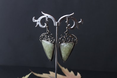 Pair of traditional Indian earrings with pearl and ruby detailing displayed on a minimalist black stand