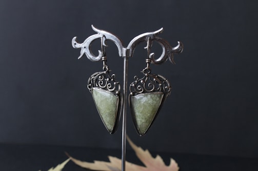 Colorful gemstone drop earrings hanging from a rustic wooden stand