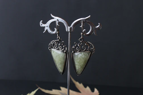 Elegant earrings with intricate filigree details displayed on a minimalist white stand.