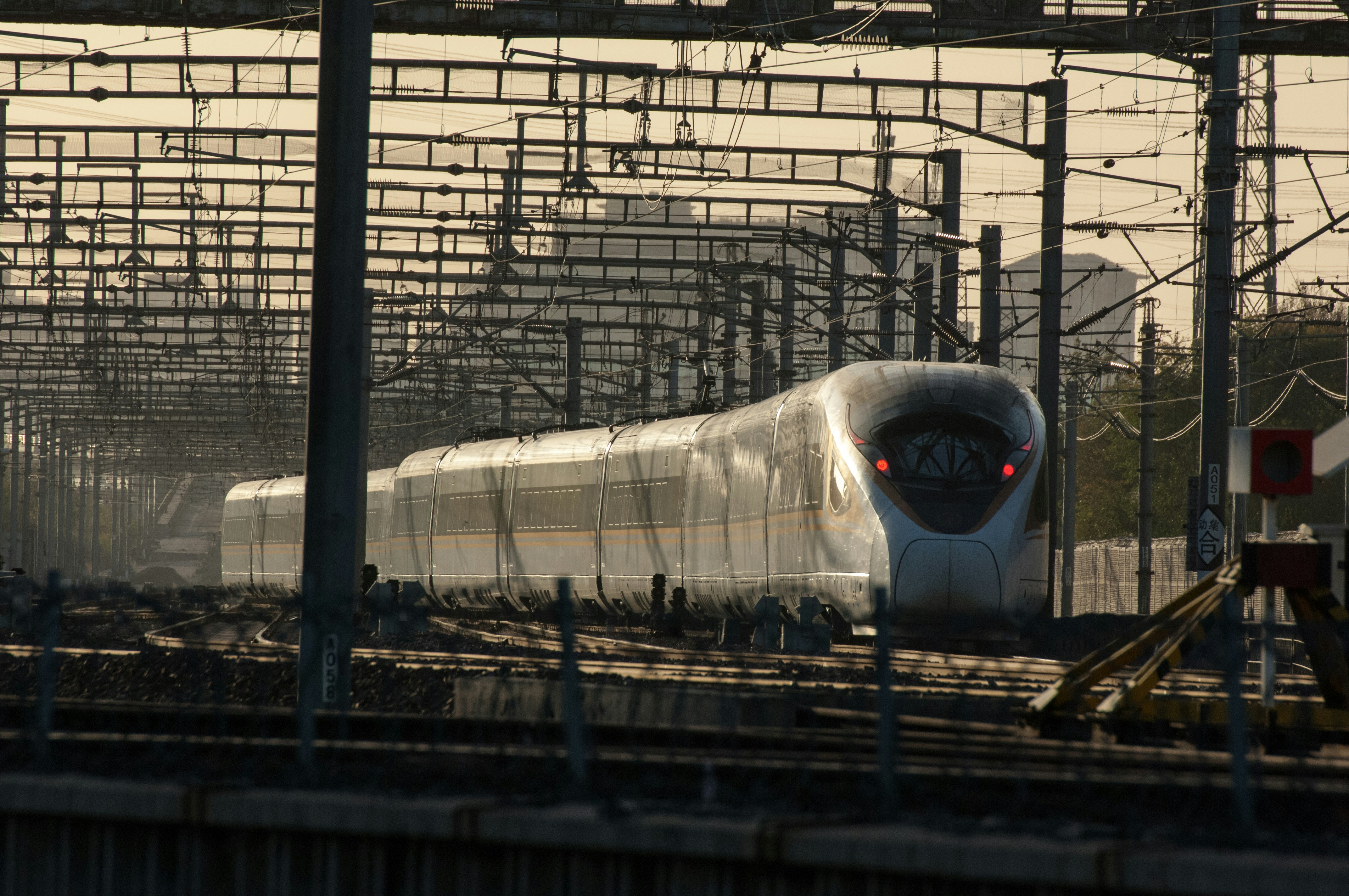 A white train traveling down train tracks next to a forest photo – Free ...