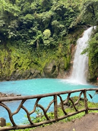 a woman standing on a bridge looking at a waterfall