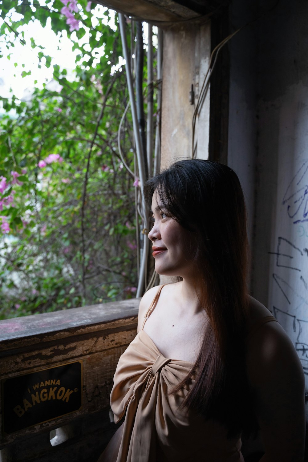 a woman looking out of a window with a tree in the background