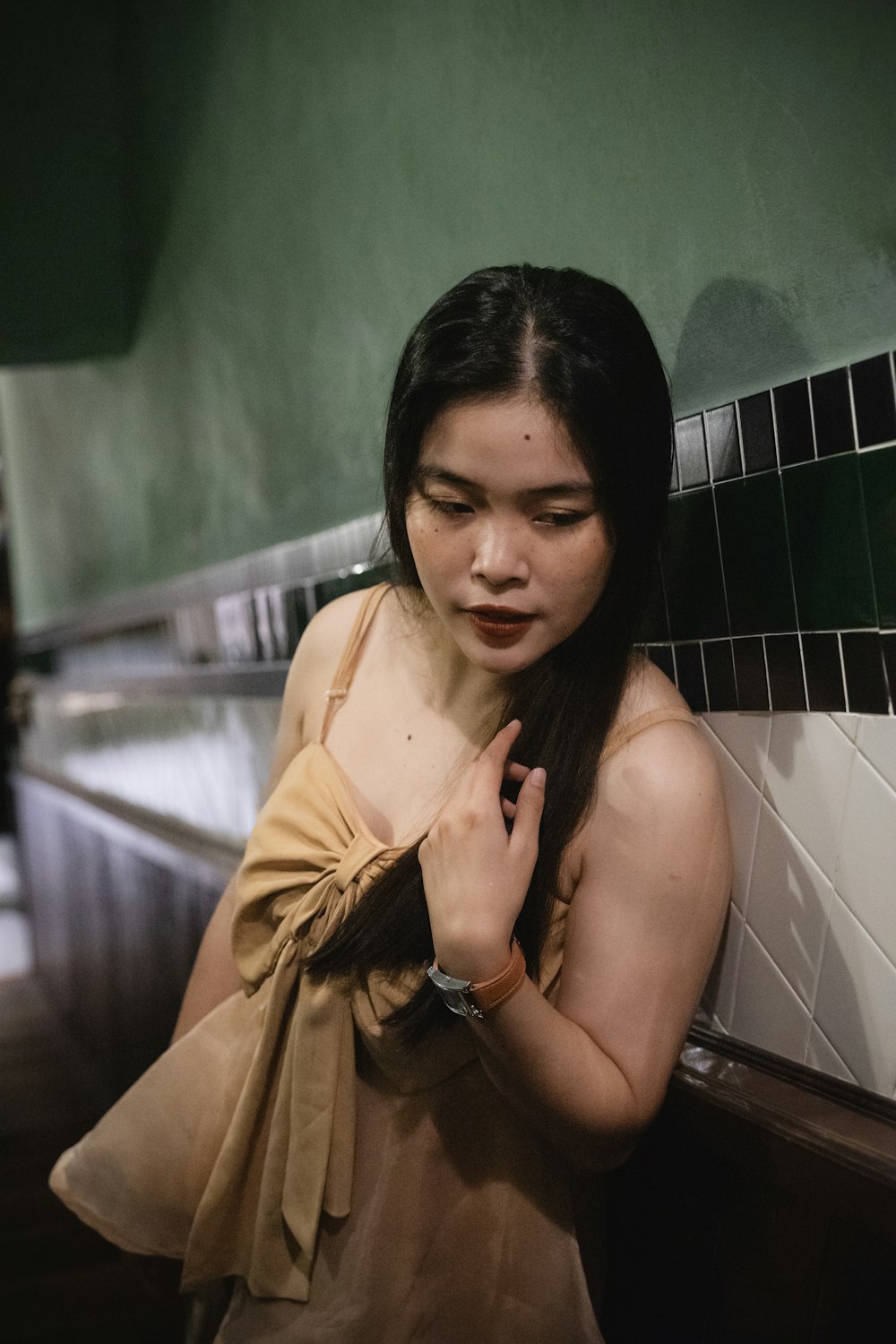 a woman standing next to a green tiled wall