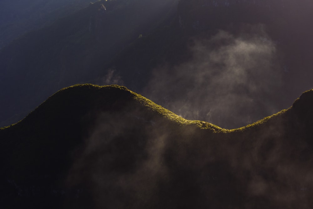 the sun shines through the clouds over a mountain