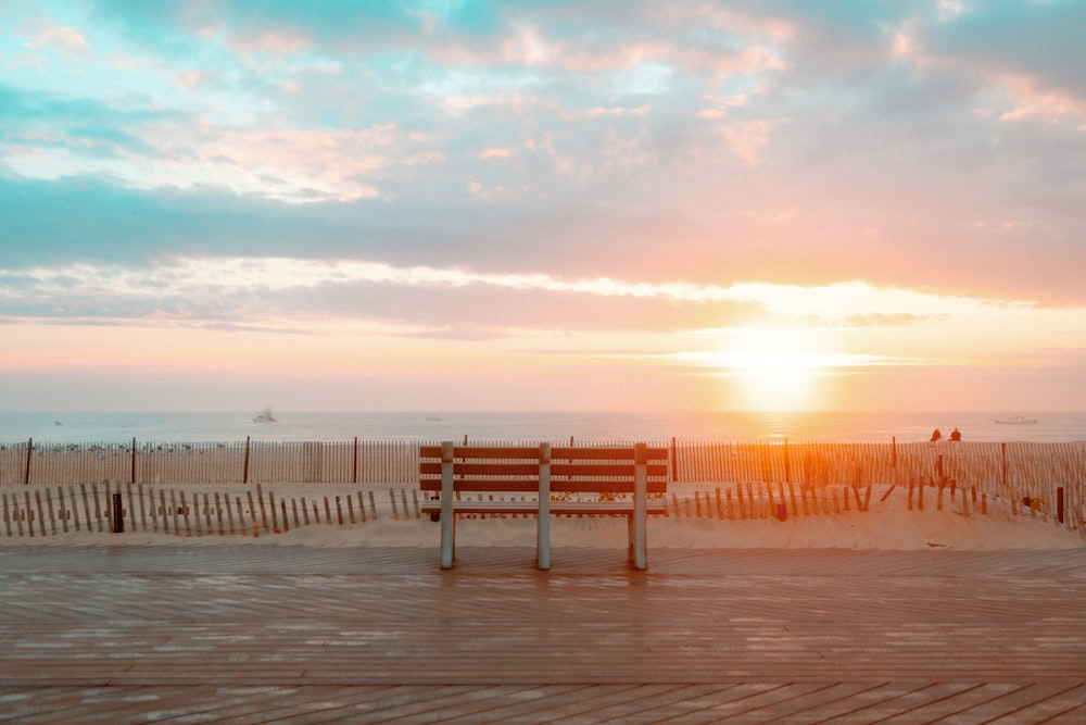 a bench sitting on top of a wooden floor next to the ocean