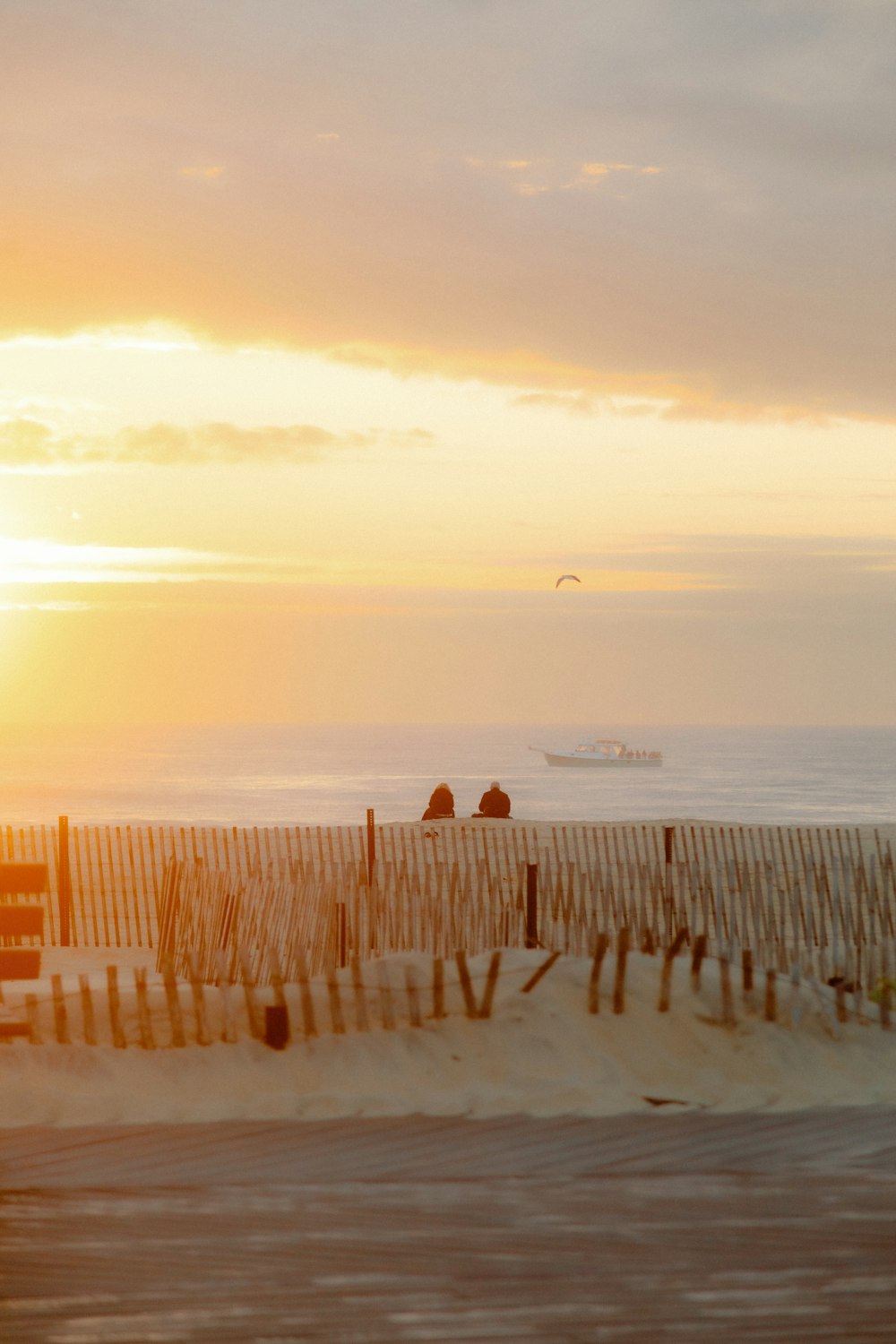 the sun is setting over the beach with people walking on the sand