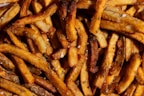 Golden crispy frozen potato fries piled in a basket with a sprinkle of salt.
