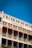 A multi-story hotel building with decorative yellow wrought iron railings and green shutters on the windows. The façade features a combination of light beige, green, and earthy red colors with the name 'Grand Hotel Imperial' prominently displayed. The sky above is clear and deep blue.