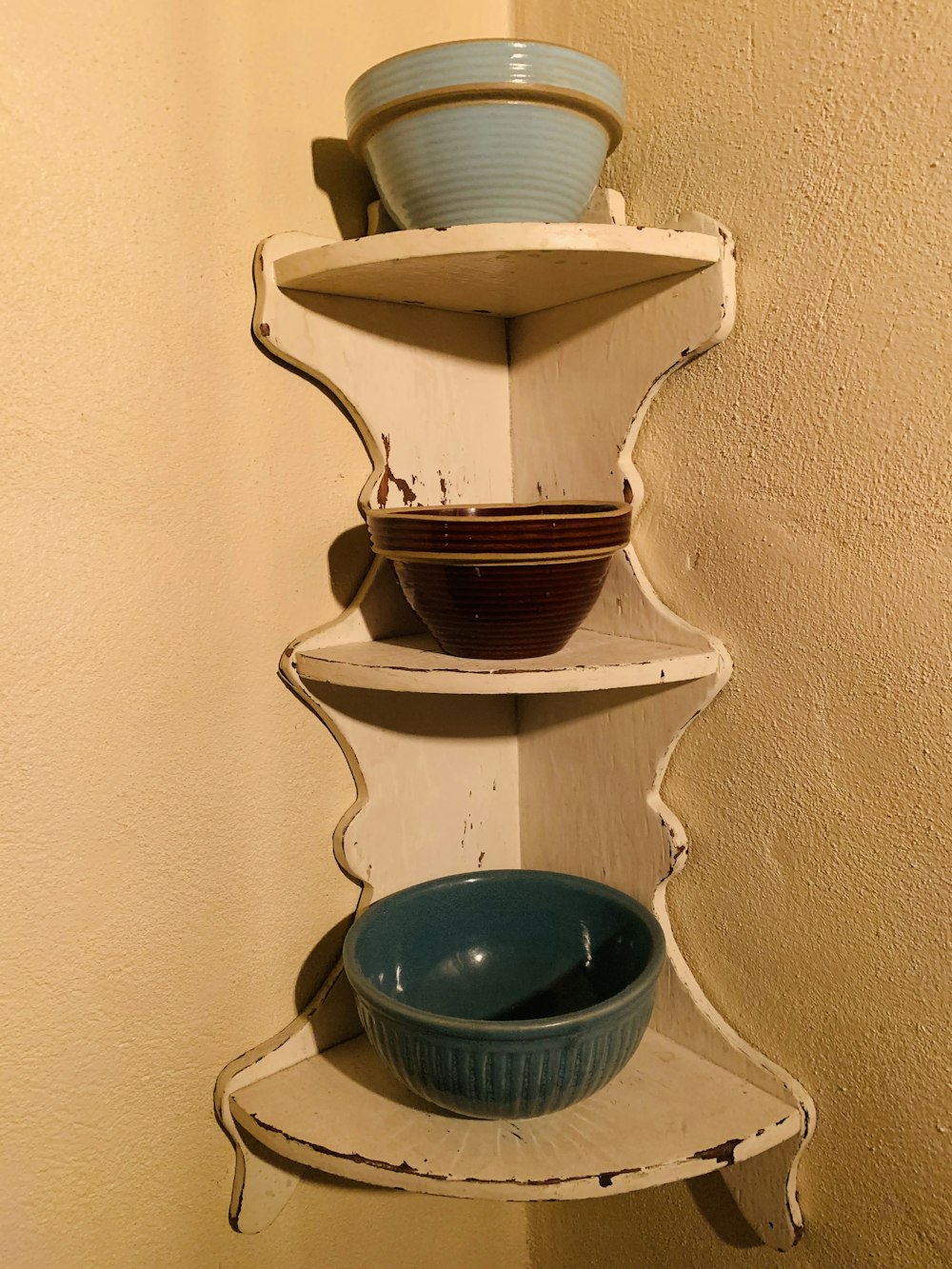 a white shelf with three bowls on top of it