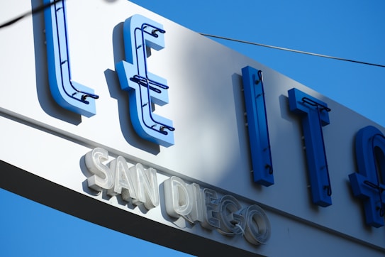 A large sign with blue neon letters partially visible, and the words 'SAN DIEGO' prominently displayed underneath in white. The background is a clear blue sky.