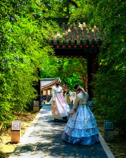 a couple of women in long dresses walking down a path