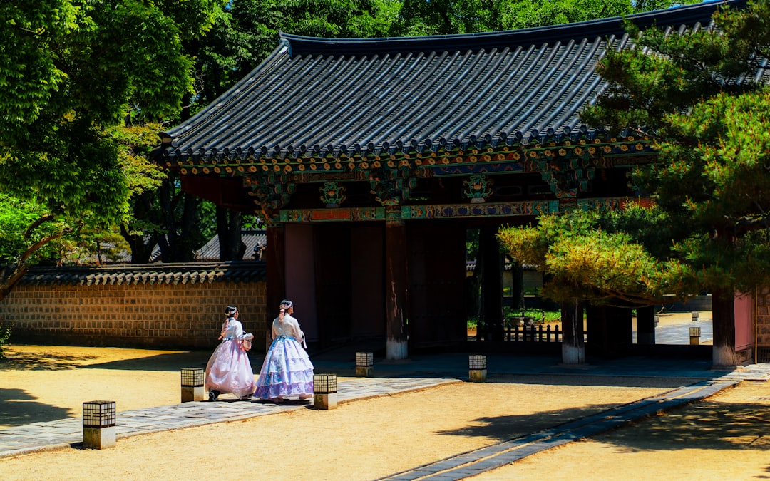 a couple of women walking down a street next to a building,