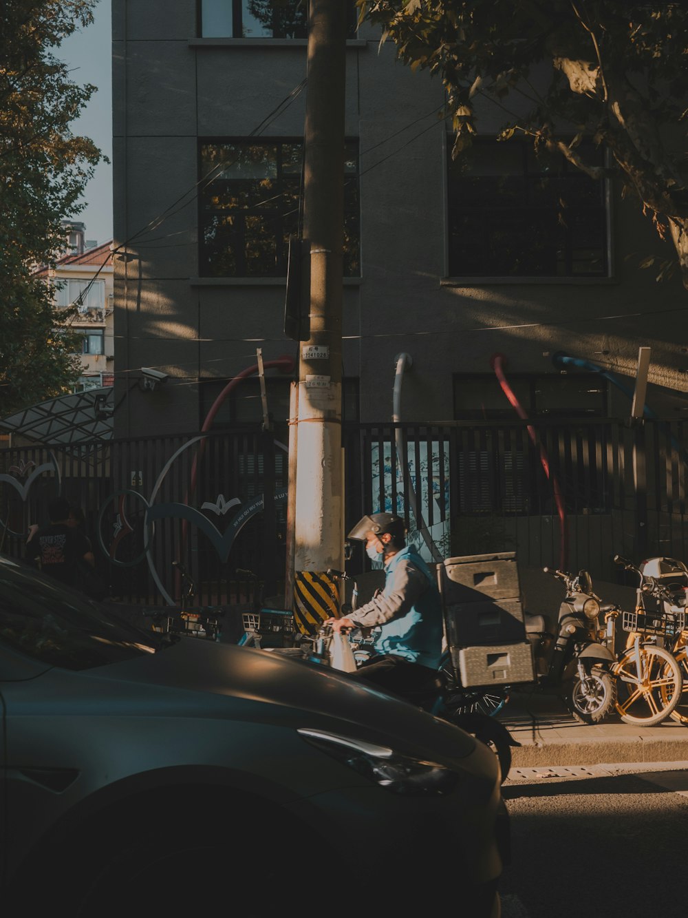 a man riding a motorcycle down a street next to a tall building