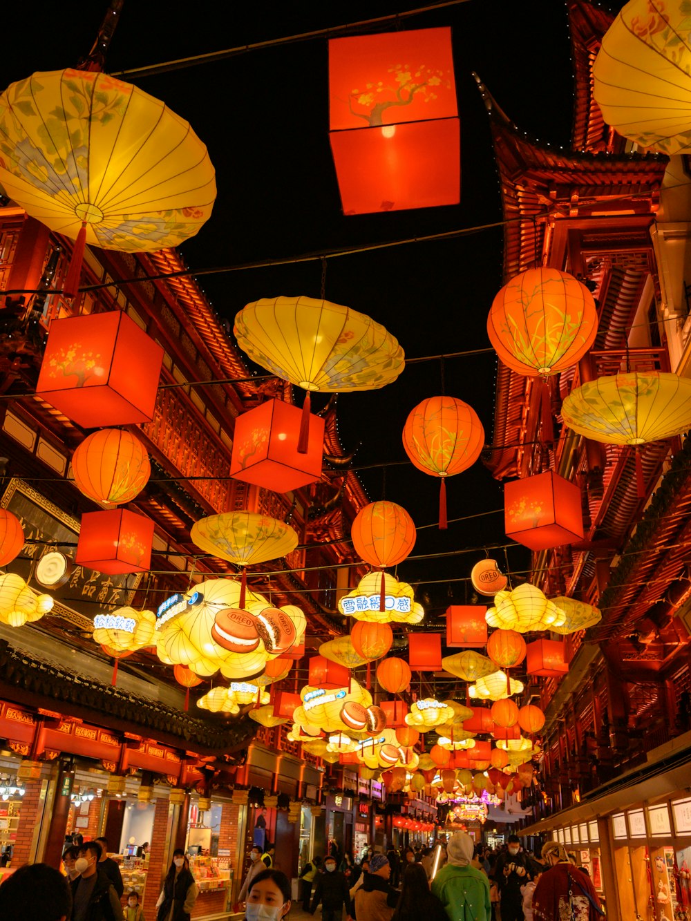 a group of people walking down a street under lots of lights