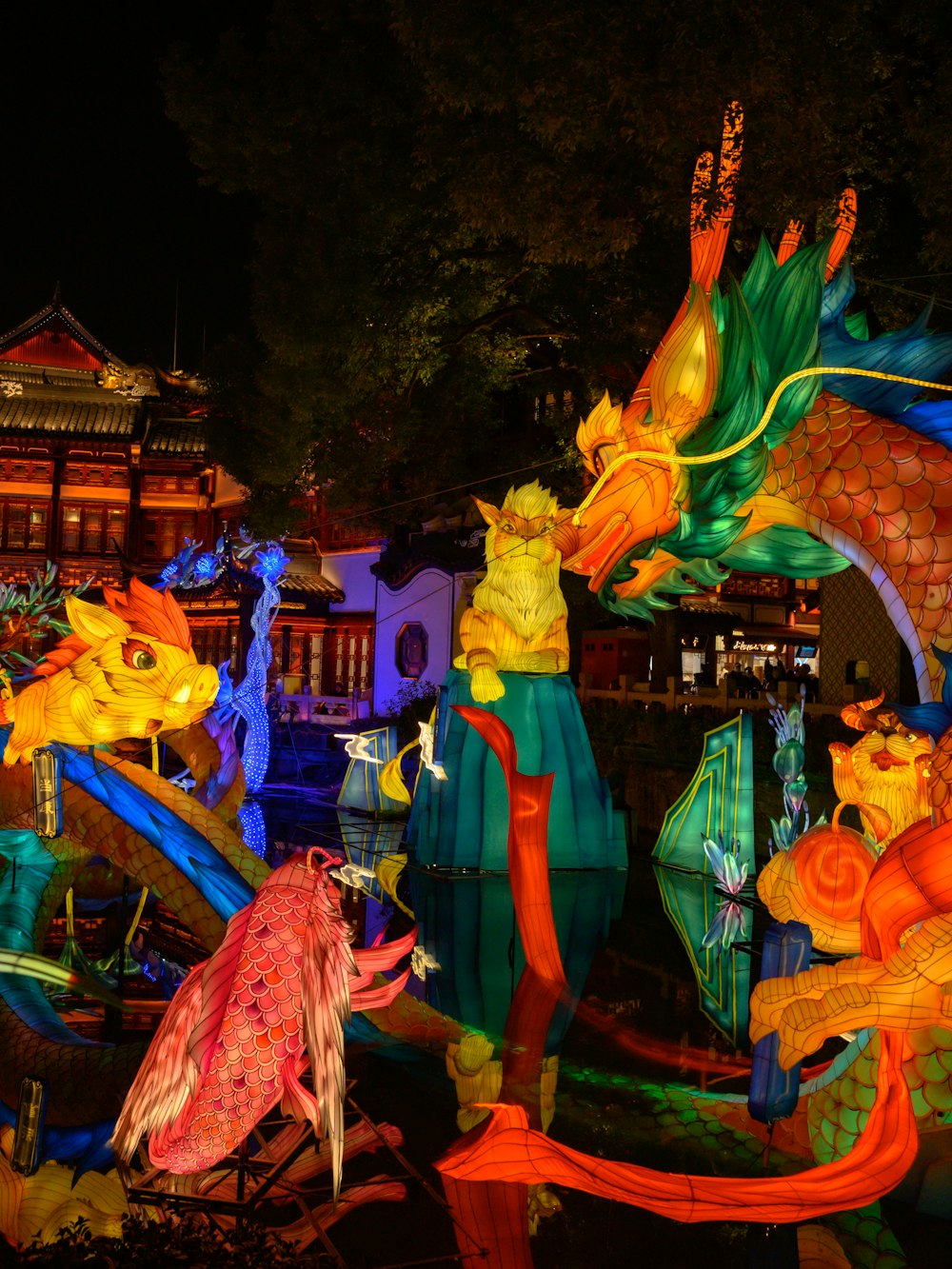 a group of colorfully lit dragon statues in a park