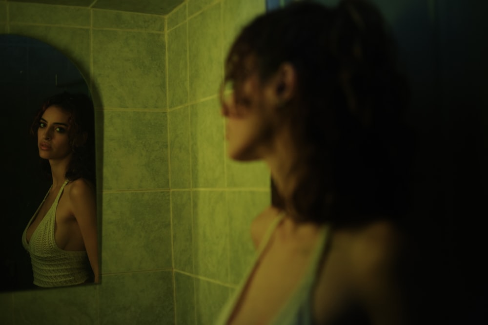 a woman standing in front of a bathroom mirror