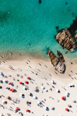 White sandy beach with colorful umbrellas and crystal-clear waves lapping the shore.