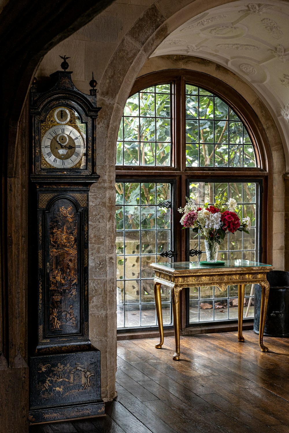 una mesa con un jarrón de flores frente a una ventana