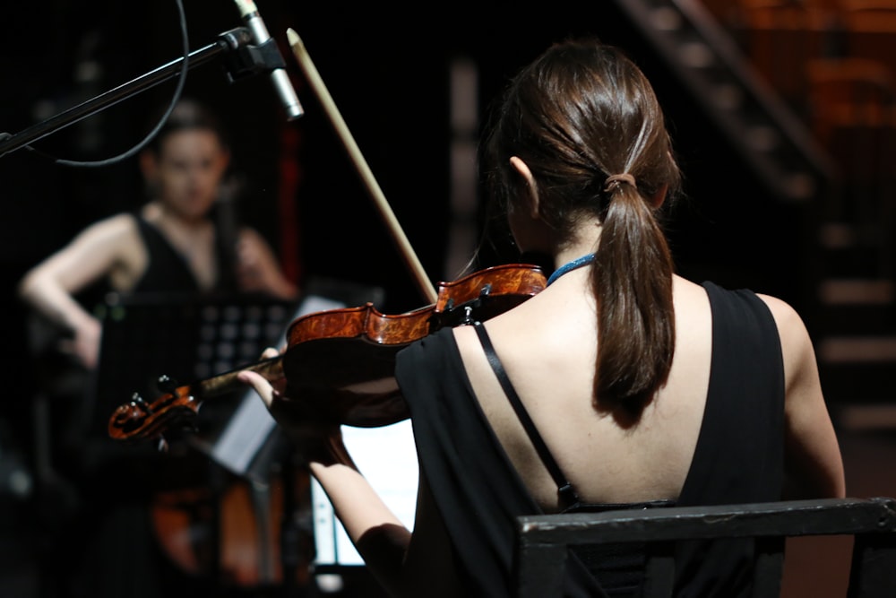 a woman playing a violin in front of a microphone
