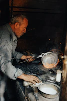 Artisan shaping iron rods with traditional tools under warm lighting.