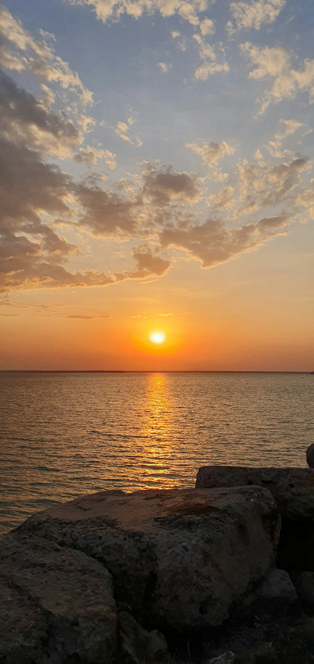 a person sitting on a rock watching the sun set