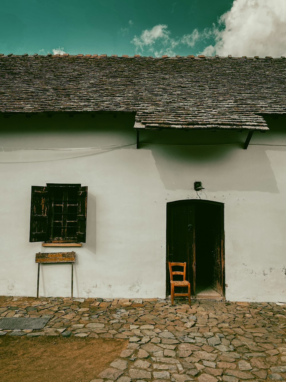 a white building with two windows and a chair in front of it