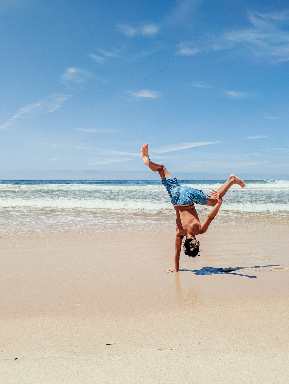 a man doing a handstand on the beach