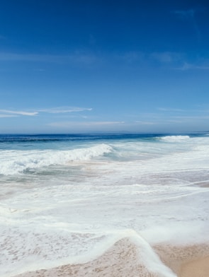 A tranquil beach scene with gentle waves and soft sand.