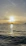A serene sunset over calm ocean waters with a sleek sailboat gliding smoothly.