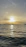 A serene sunset over calm ocean waters with a sleek sailboat gliding smoothly.