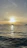 A serene sunset over calm ocean waters with a sleek sailboat gliding smoothly.