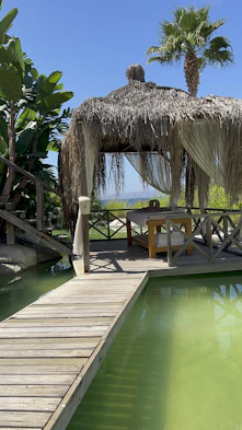 a gazebo next to a pool with a table and chairs