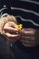 Hands gently holding a small, intricate crochet flower symbolizing care and creativity.