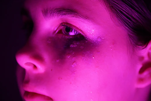 A close-up of glowing skin illuminated by soft pastel light, highlighting natural radiance.