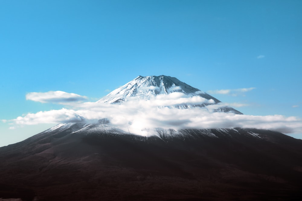 a mountain covered in clouds under a blue sky