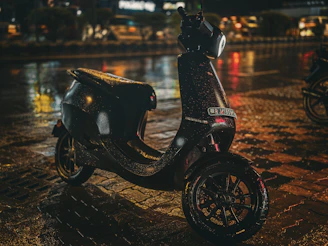A sleek axv tm-fs electric scooter gliding smoothly on an urban street at dusk, with city lights reflecting off its carbon black frame.