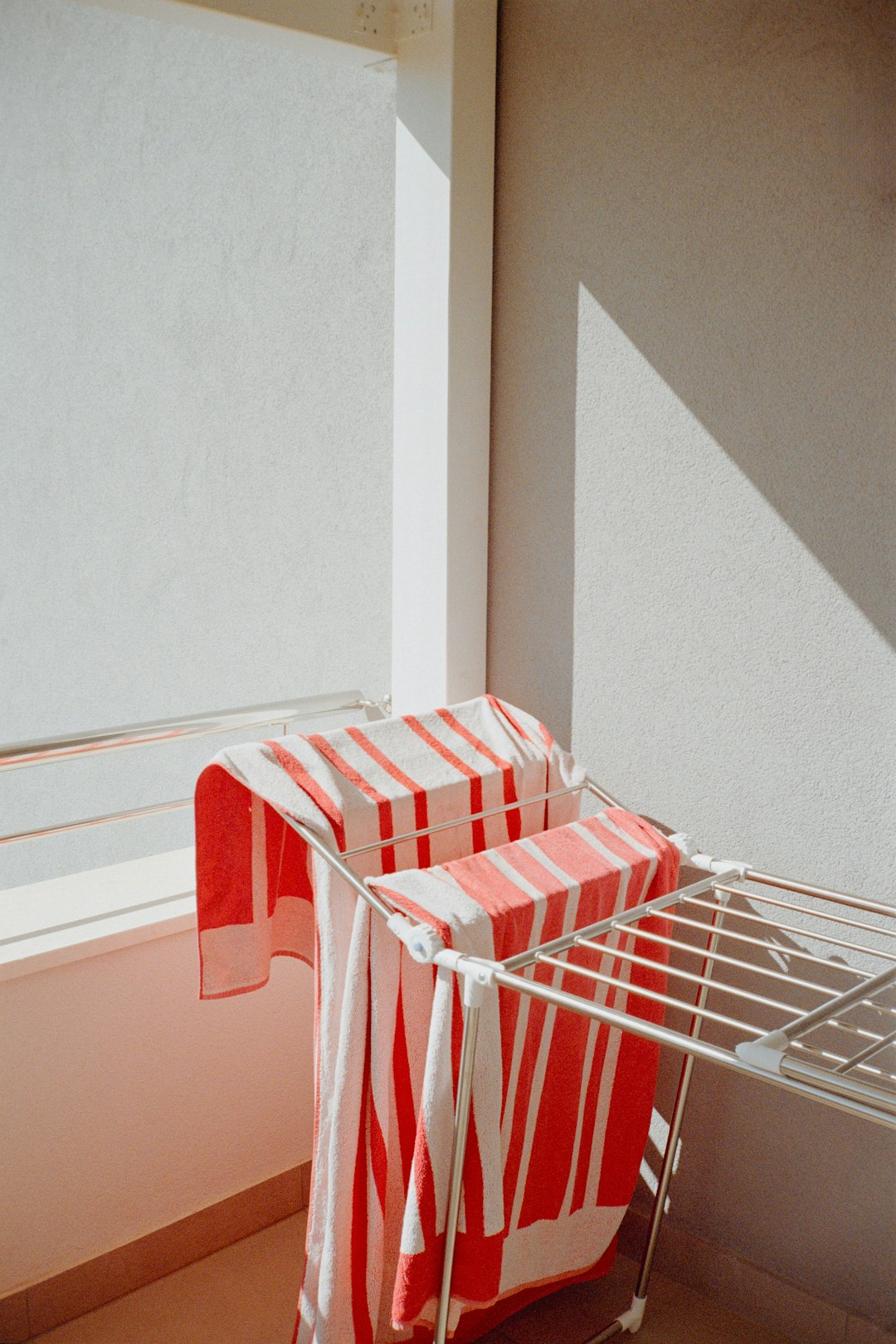 Clothes drying rack with striped towels in sunlight