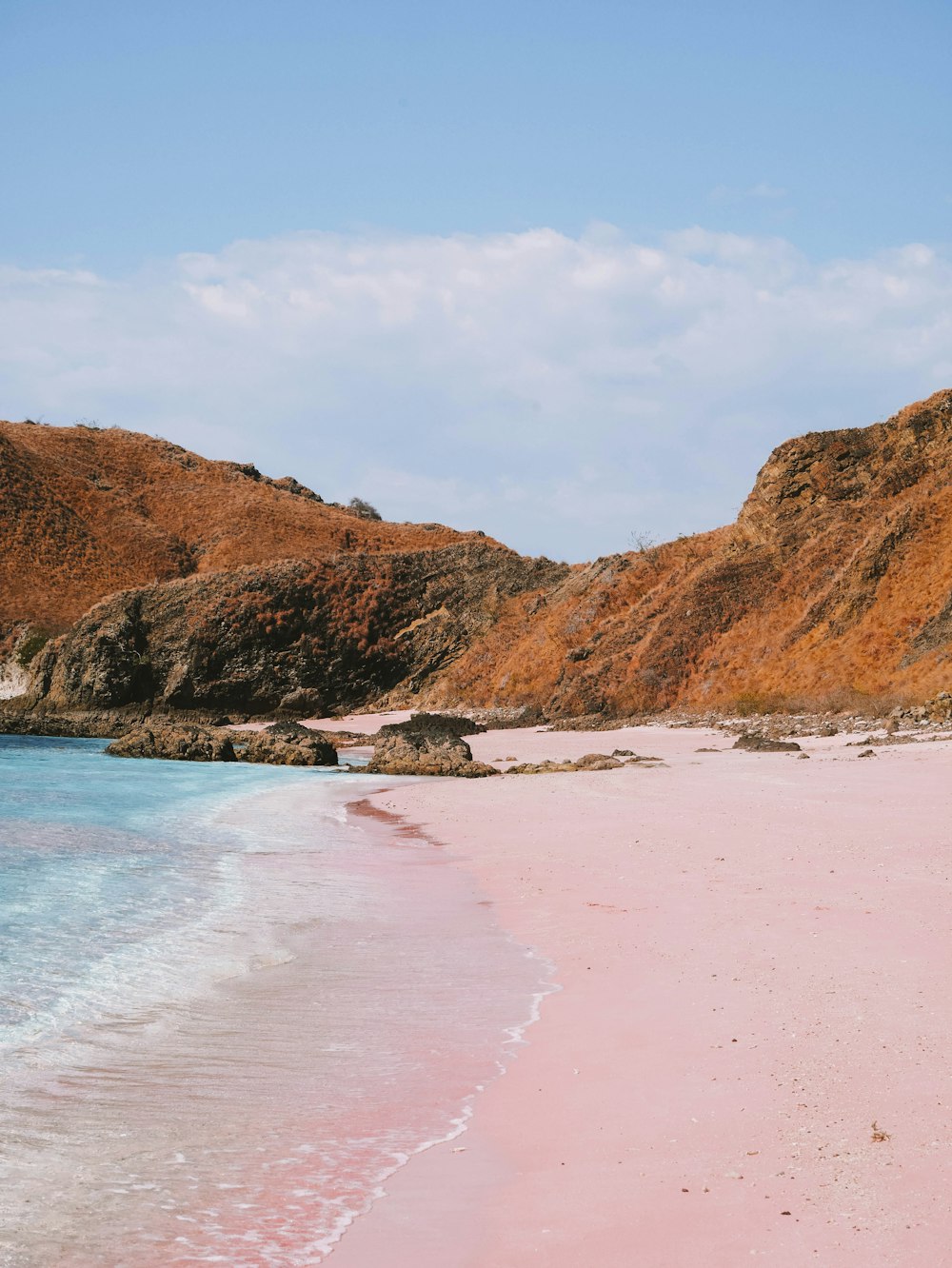 a beach with a pink sand and blue water