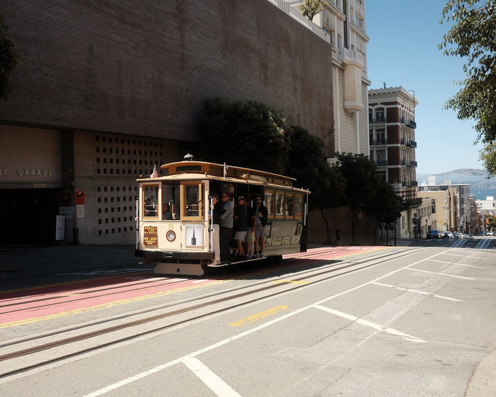 a cable car traveling down a street next to a tall building