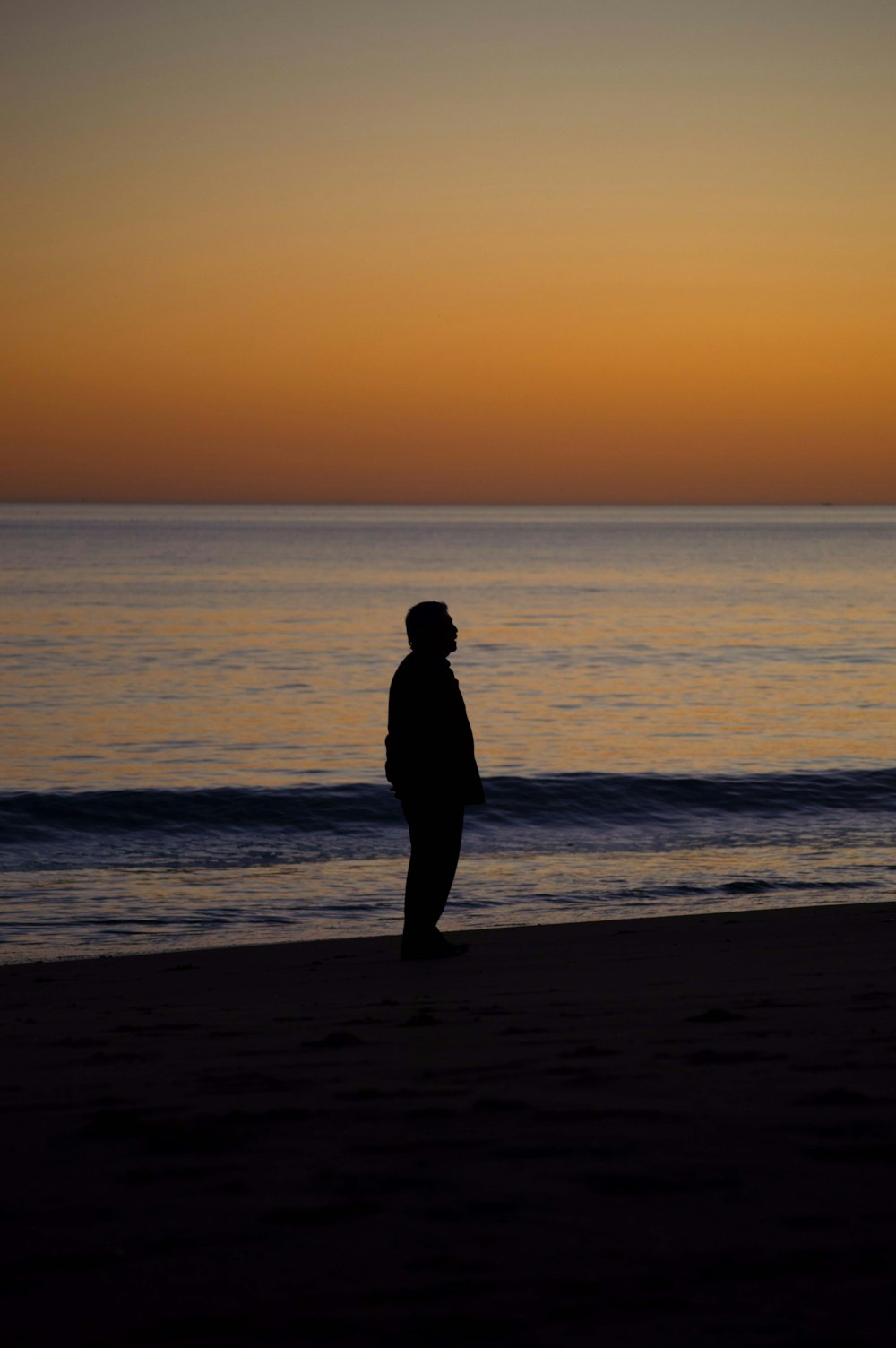 a person standing on a beach at sunset