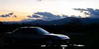 A scenic highway with a rental car parked beside a mountain viewpoint during golden hour.